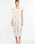 Woman wearing a white dress with colorful floral patterns on a white background