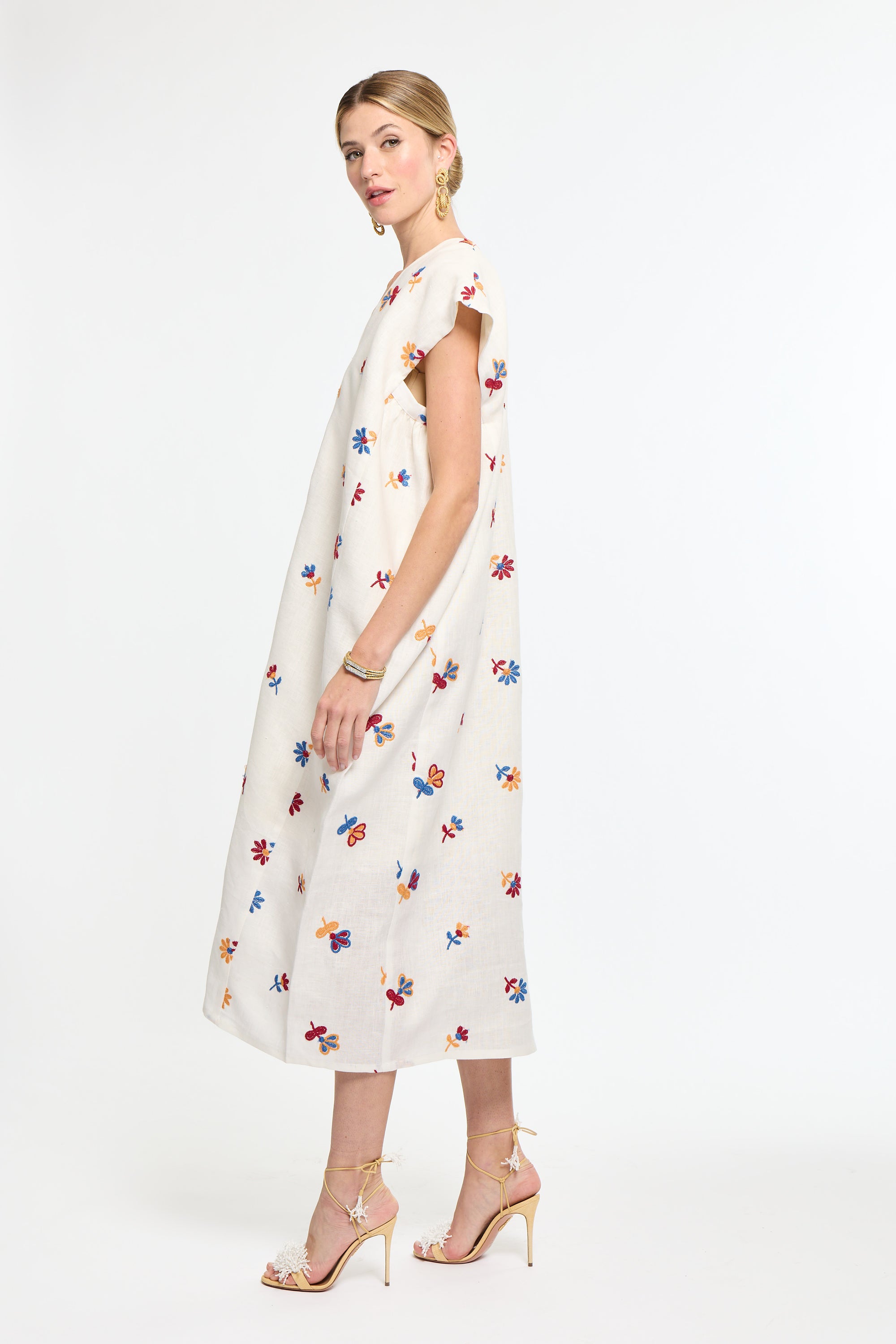 Woman wearing a white dress with colorful floral pattern on a white background