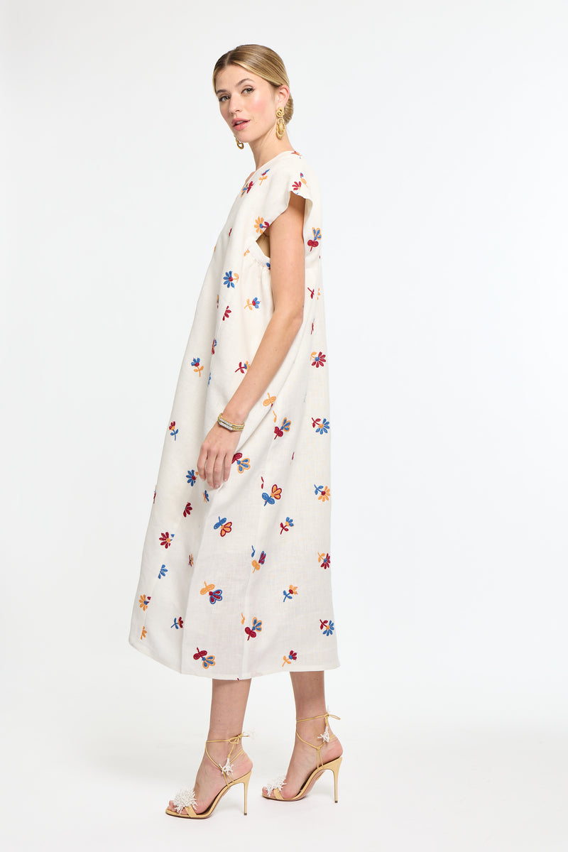 Woman wearing a white dress with colorful floral pattern on a white background