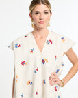 Woman wearing a white dress with colorful floral patterns on a white background
