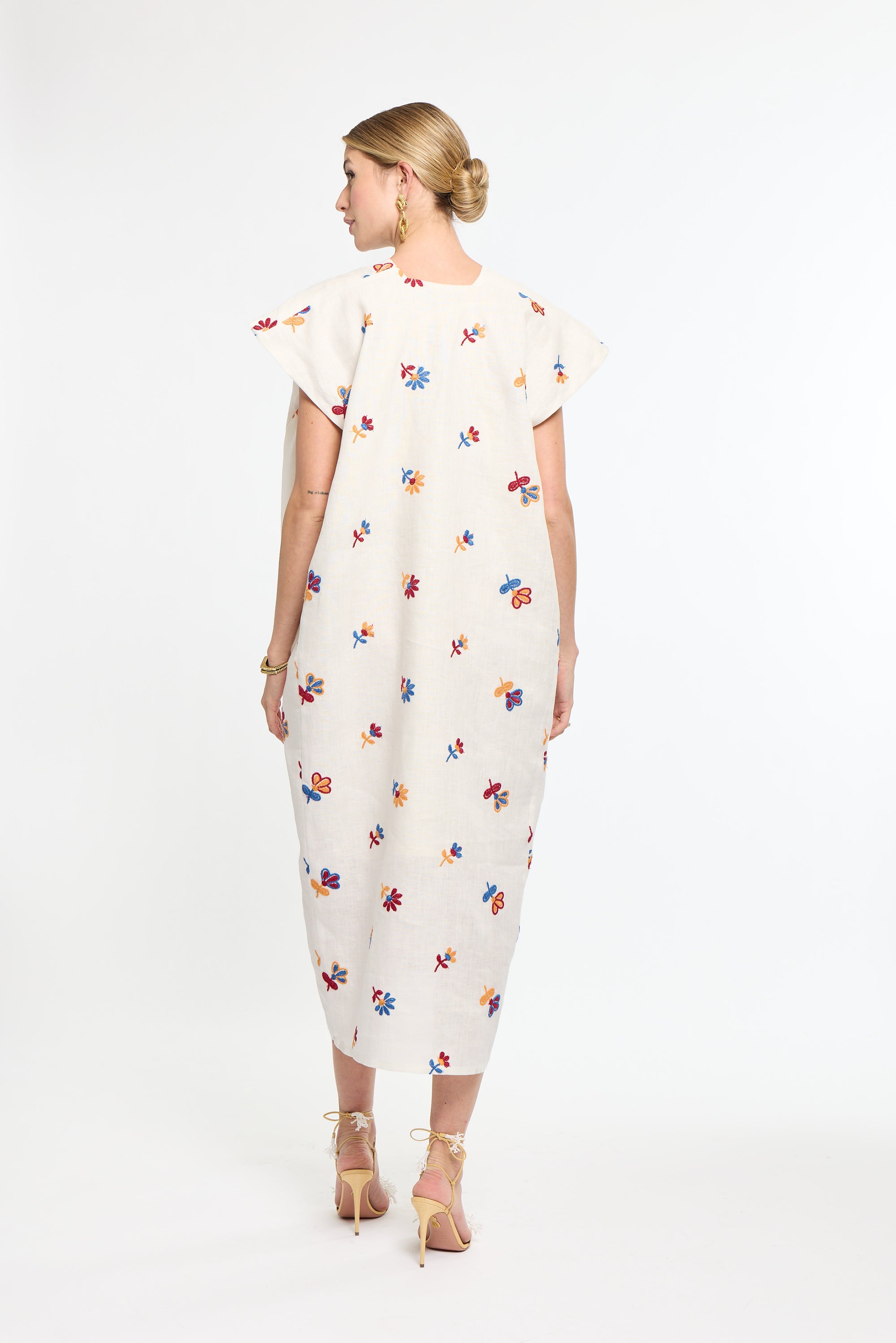 Woman wearing a white dress with colorful floral pattern on a white background
