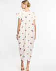 Woman wearing a white dress with colorful floral pattern on a white background