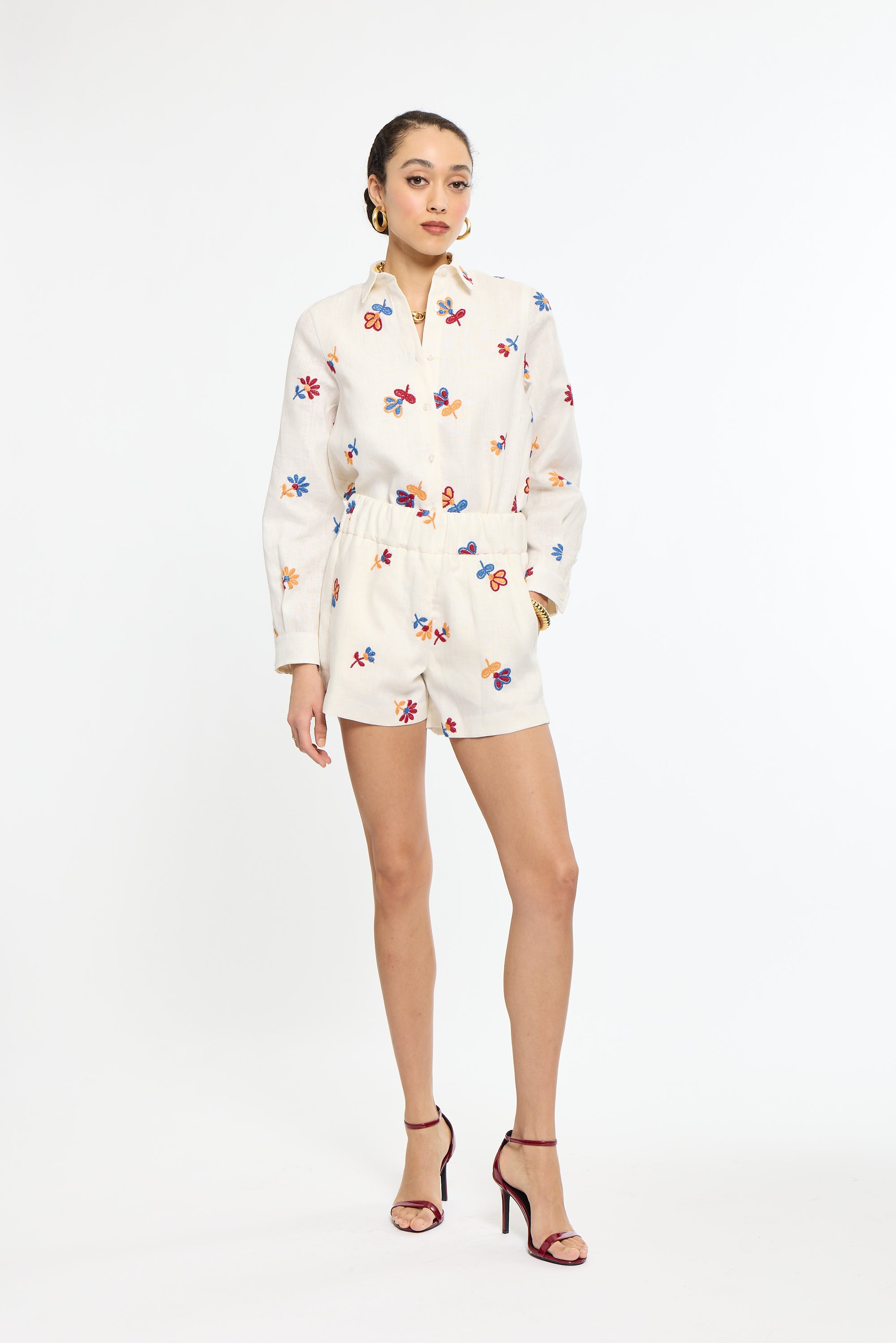 Woman wearing a white outfit with colorful floral patterns on a white background