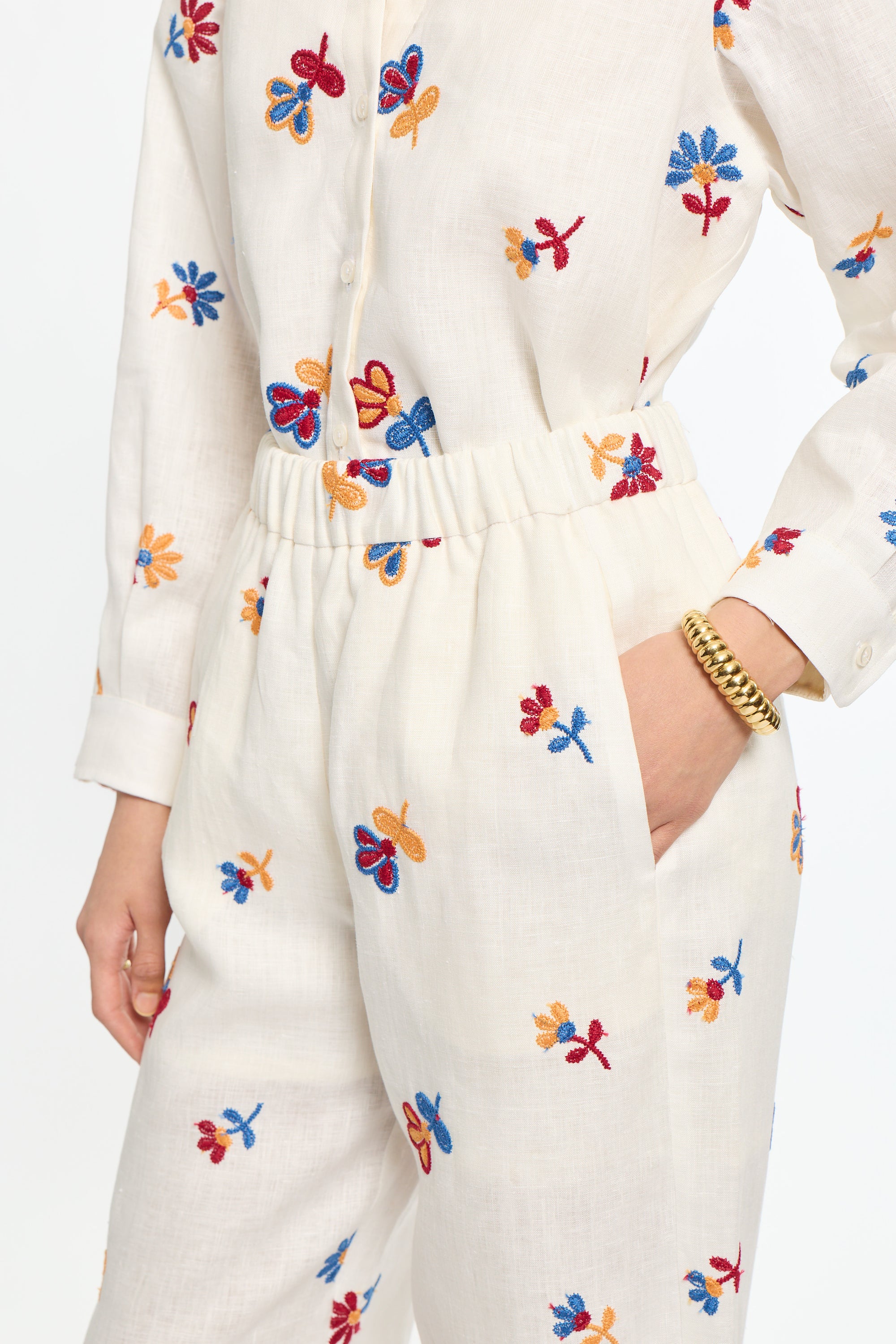 White outfit with colorful floral embroidery on a white background