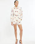 Woman wearing a white outfit with colorful floral patterns on a white background