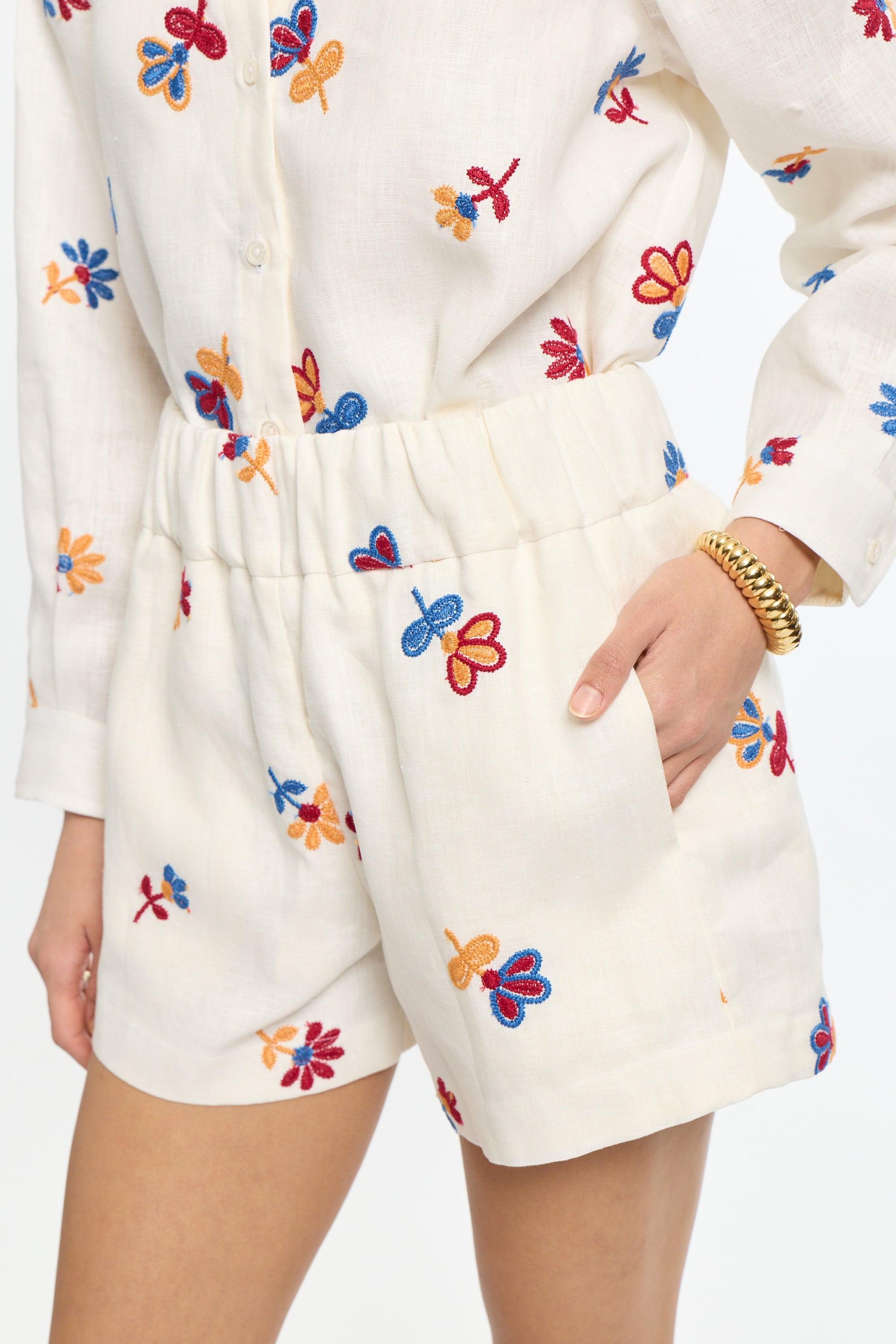 Person wearing a white outfit with colorful butterfly patterns on a plain background