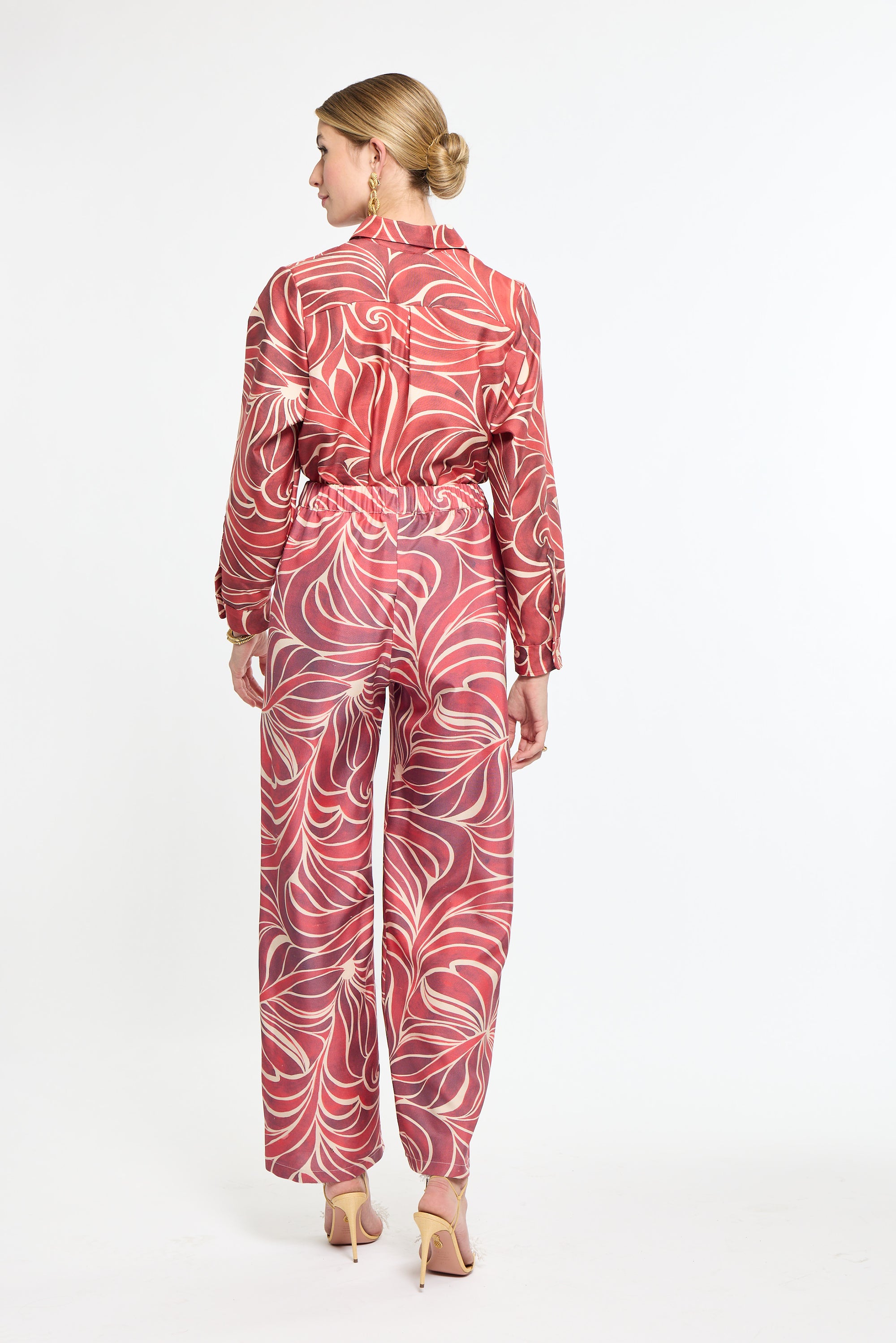 Woman wearing a red and white patterned jumpsuit on a white background