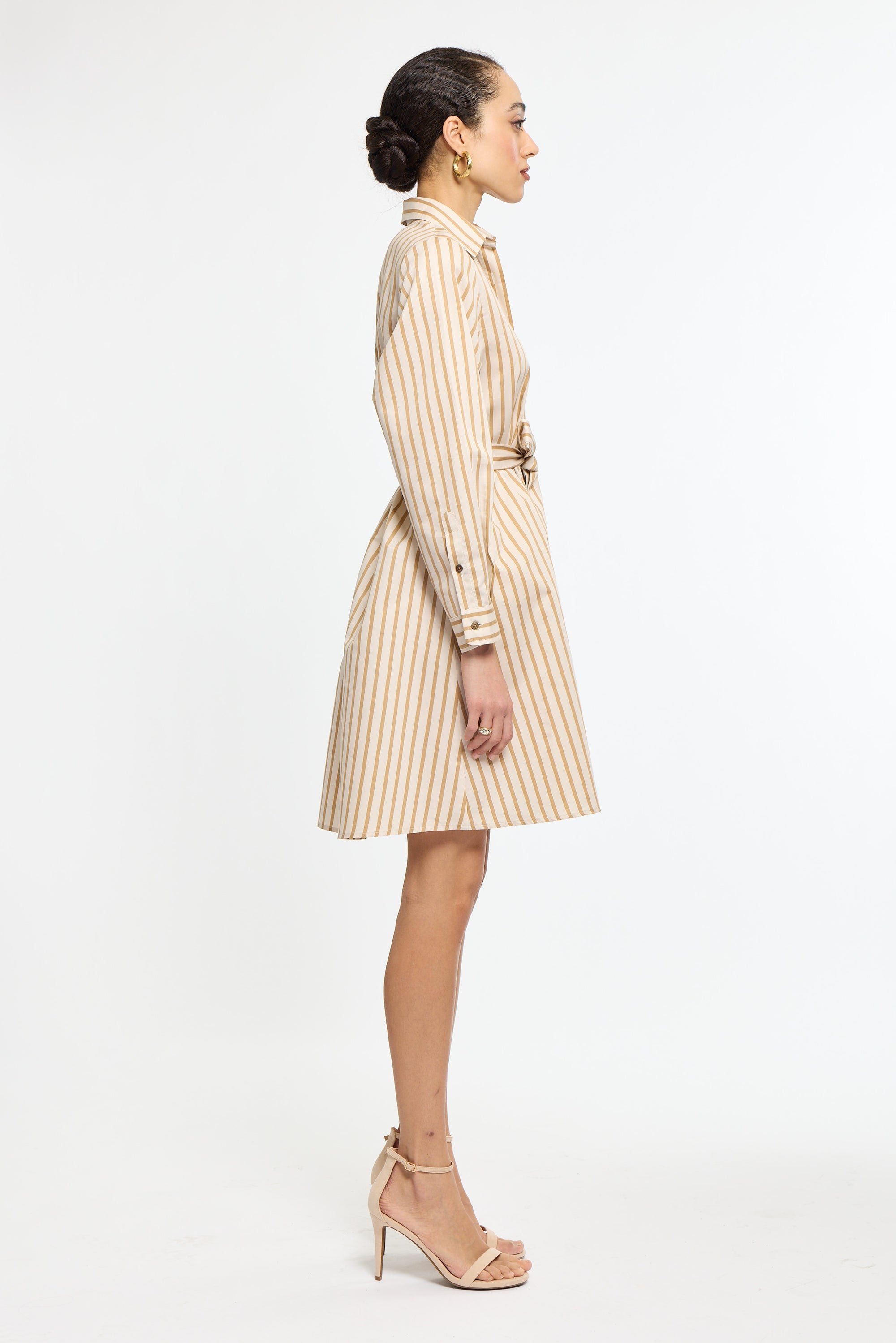 Woman wearing a beige and white striped dress on a white background