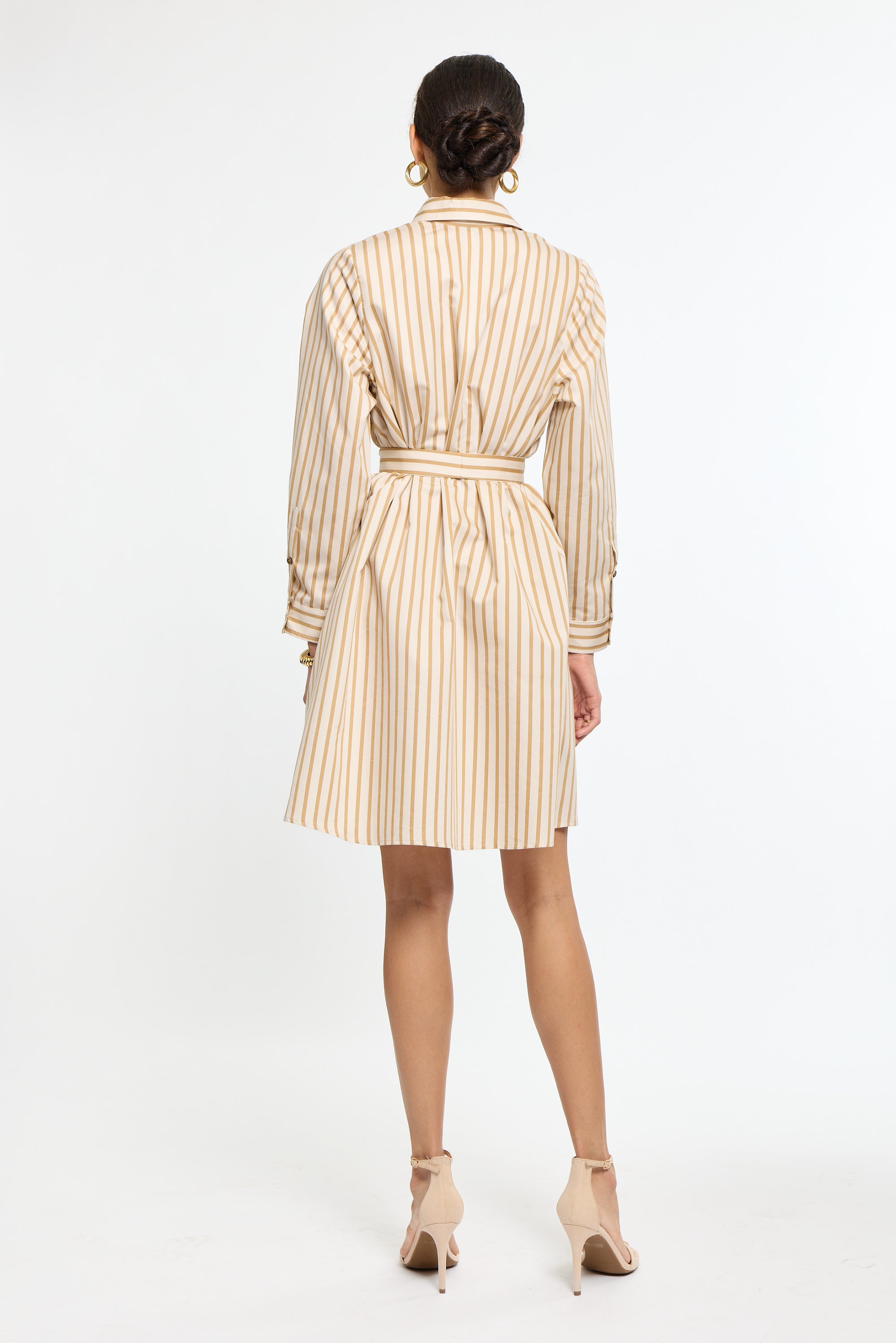 Woman wearing a beige and white striped dress on a white background