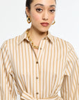 Woman wearing a beige and brown striped dress with a white background