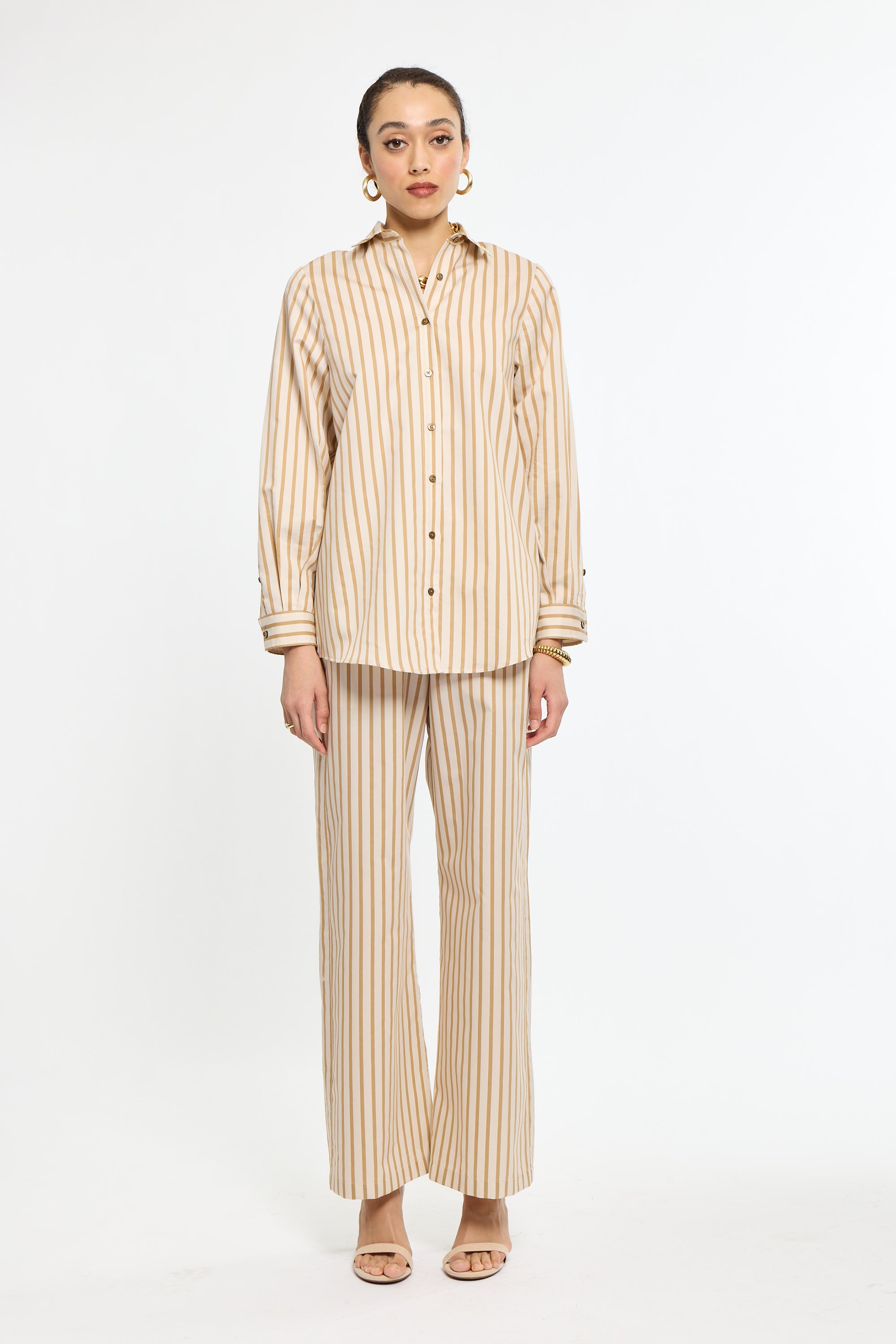 Woman wearing a beige and white striped shirt and pants on a white background