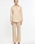 Woman wearing a beige and white striped shirt and pants on a white background