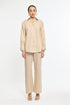 Woman wearing a beige and white striped shirt and pants on a white background