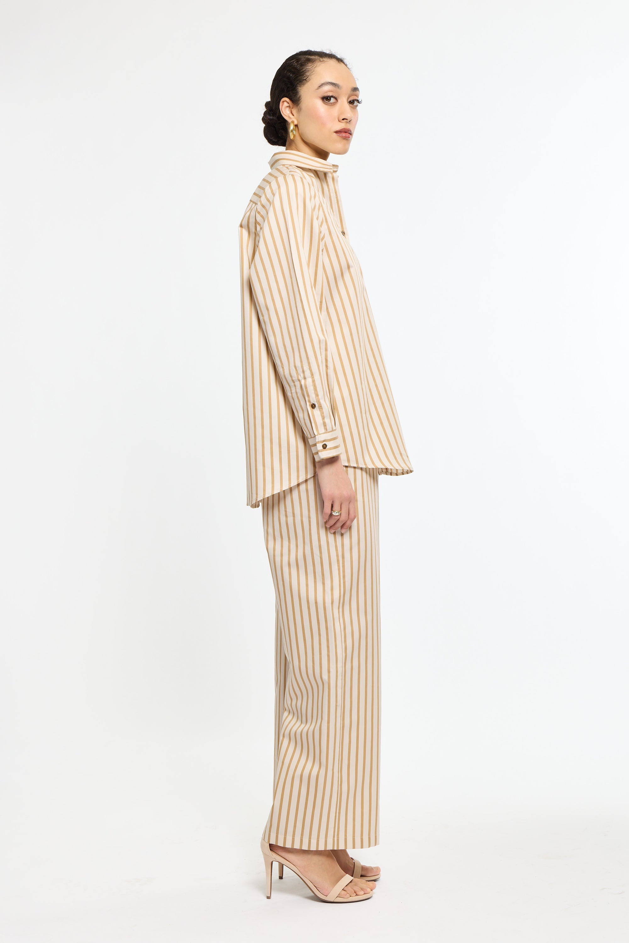 Woman wearing a beige and white striped suit on a white background