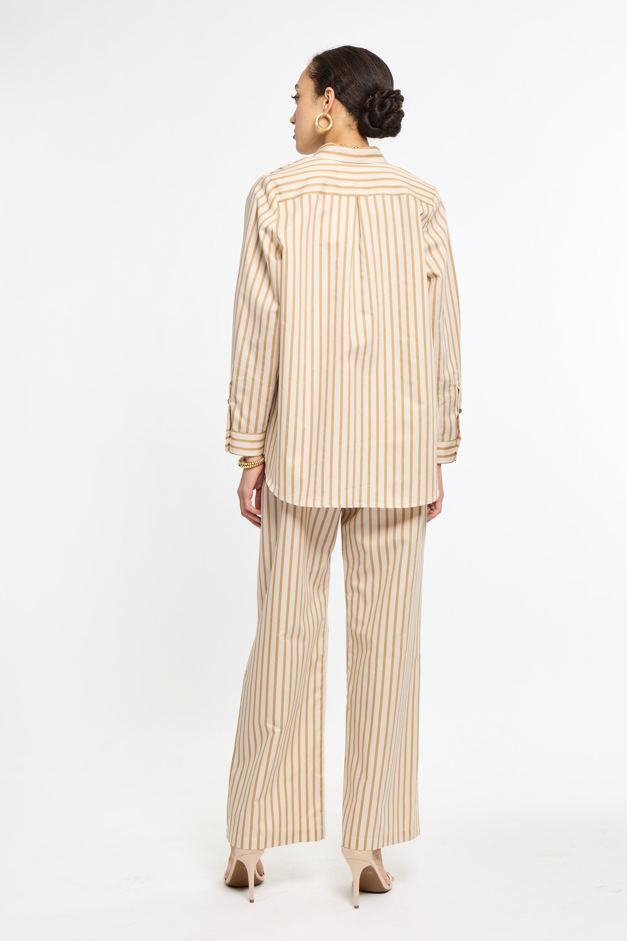 Woman wearing a beige and white striped suit on a white background