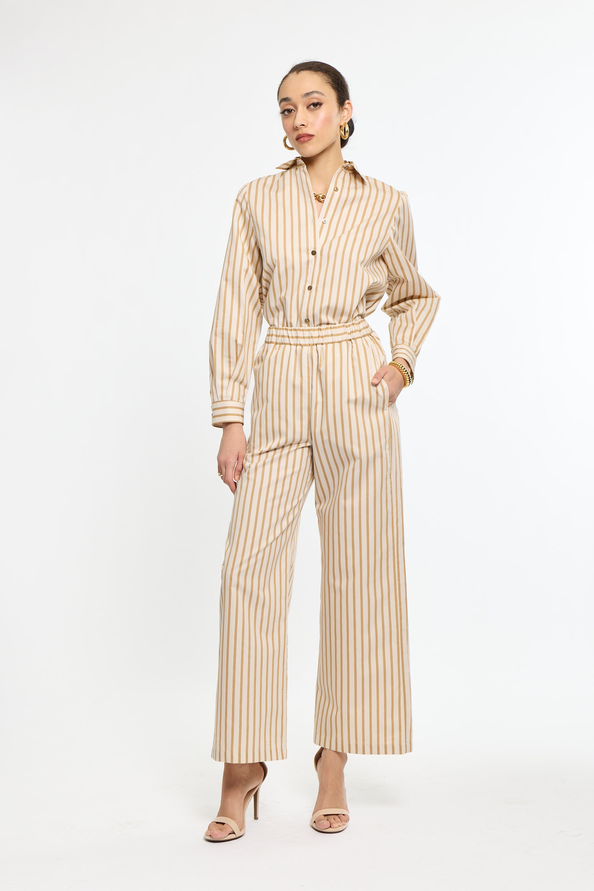 Woman wearing a beige and white striped jumpsuit on a white background