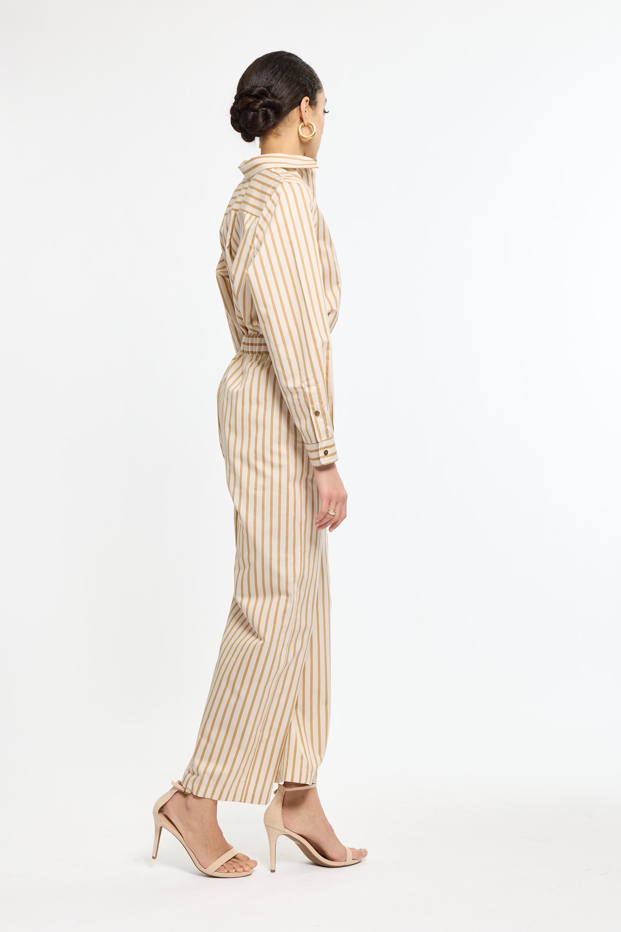 Woman wearing a beige and white striped dress on a white background