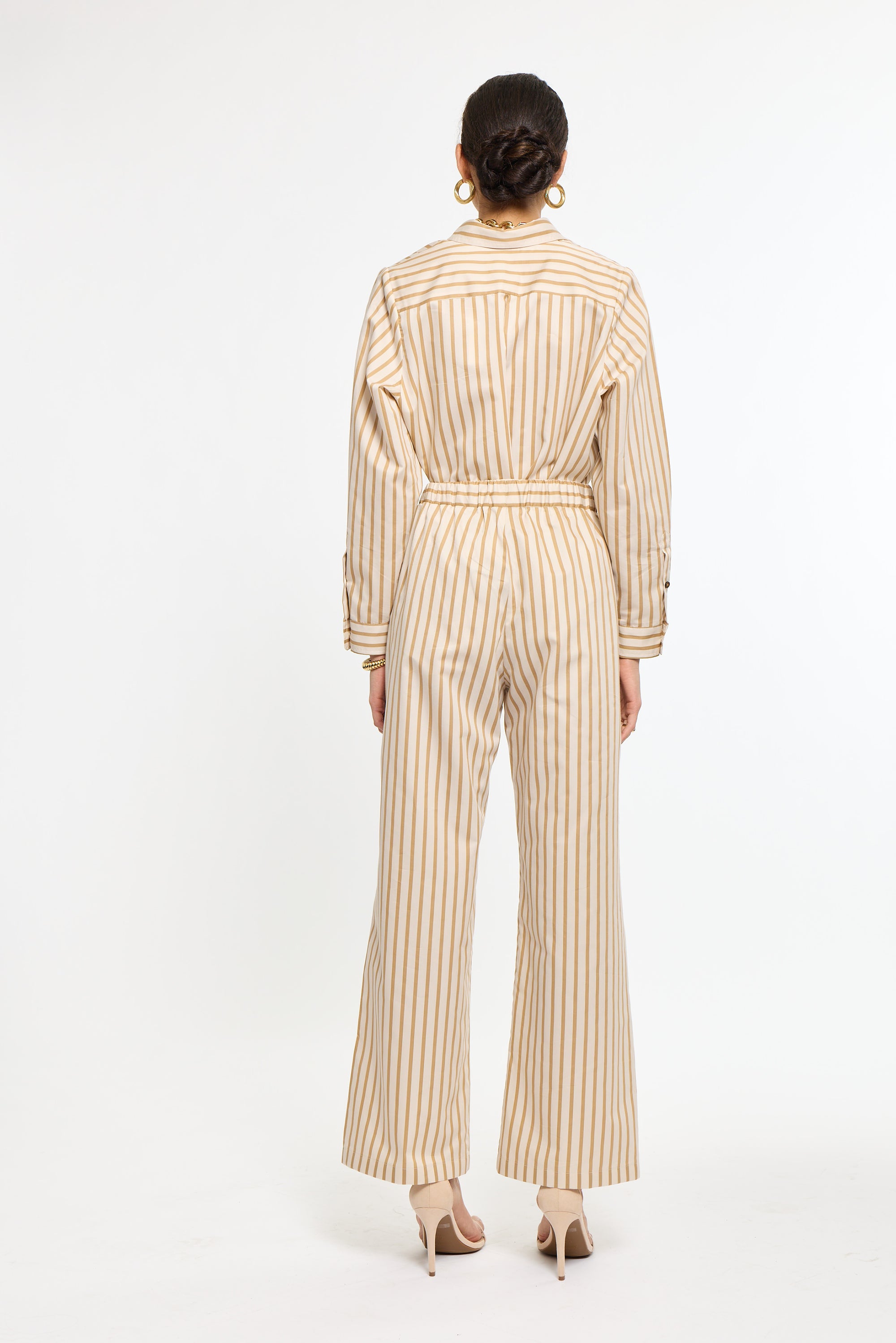 Person wearing a beige and white striped jumpsuit on a white background