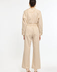 Person wearing a beige and white striped jumpsuit on a white background