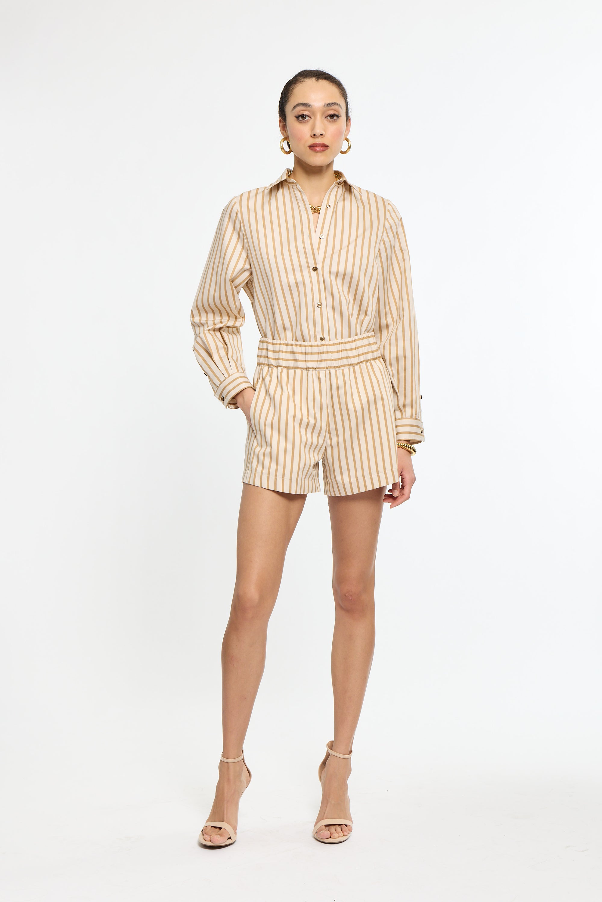 A woman with striped shorts and striped shirt in beige and tan. 