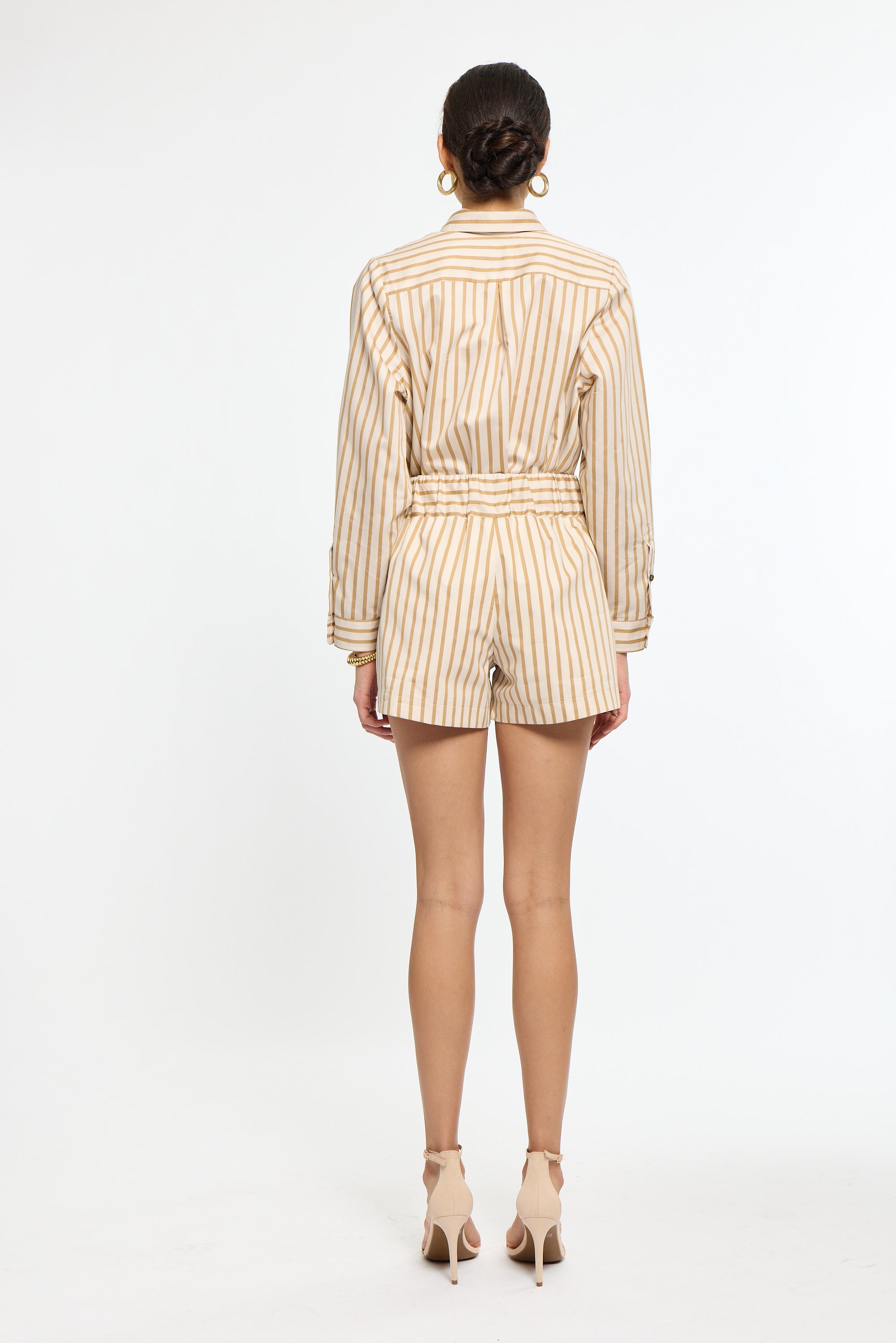 Woman wearing a striped beige and white outfit on a white background