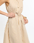 Woman wearing a beige and white striped dress on a plain background