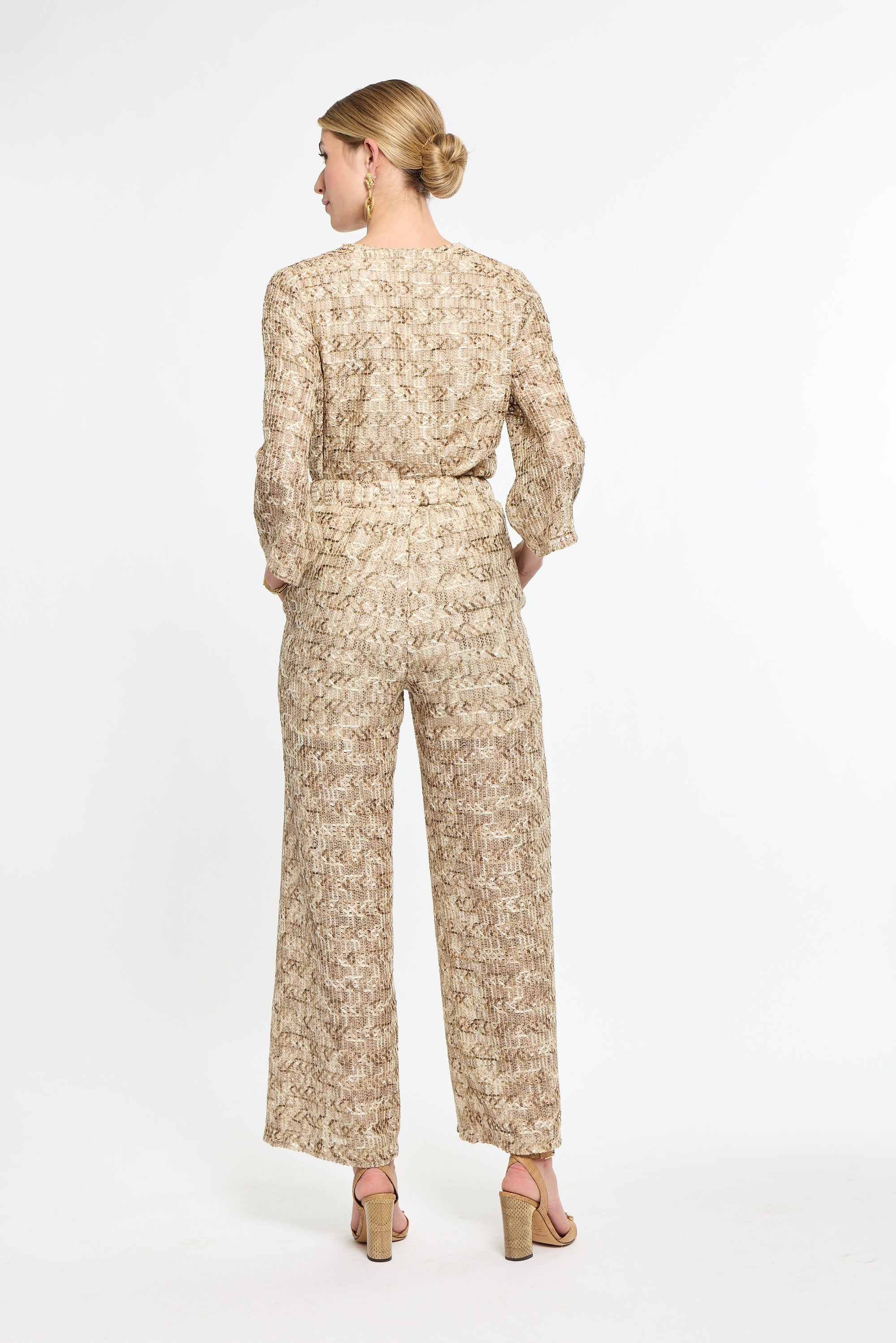 Woman wearing a beige floral jumpsuit on a white background