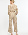 Woman wearing a beige floral jumpsuit on a white background