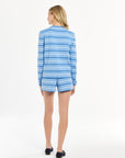 Woman dressed in a blue striped set, captured against a clean white background.
