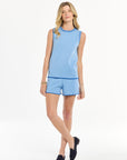 Woman wearing a light blue sleeveless top and shorts set on a white background