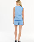 Woman wearing a light blue sleeveless top and shorts set with dark blue trim on a white background