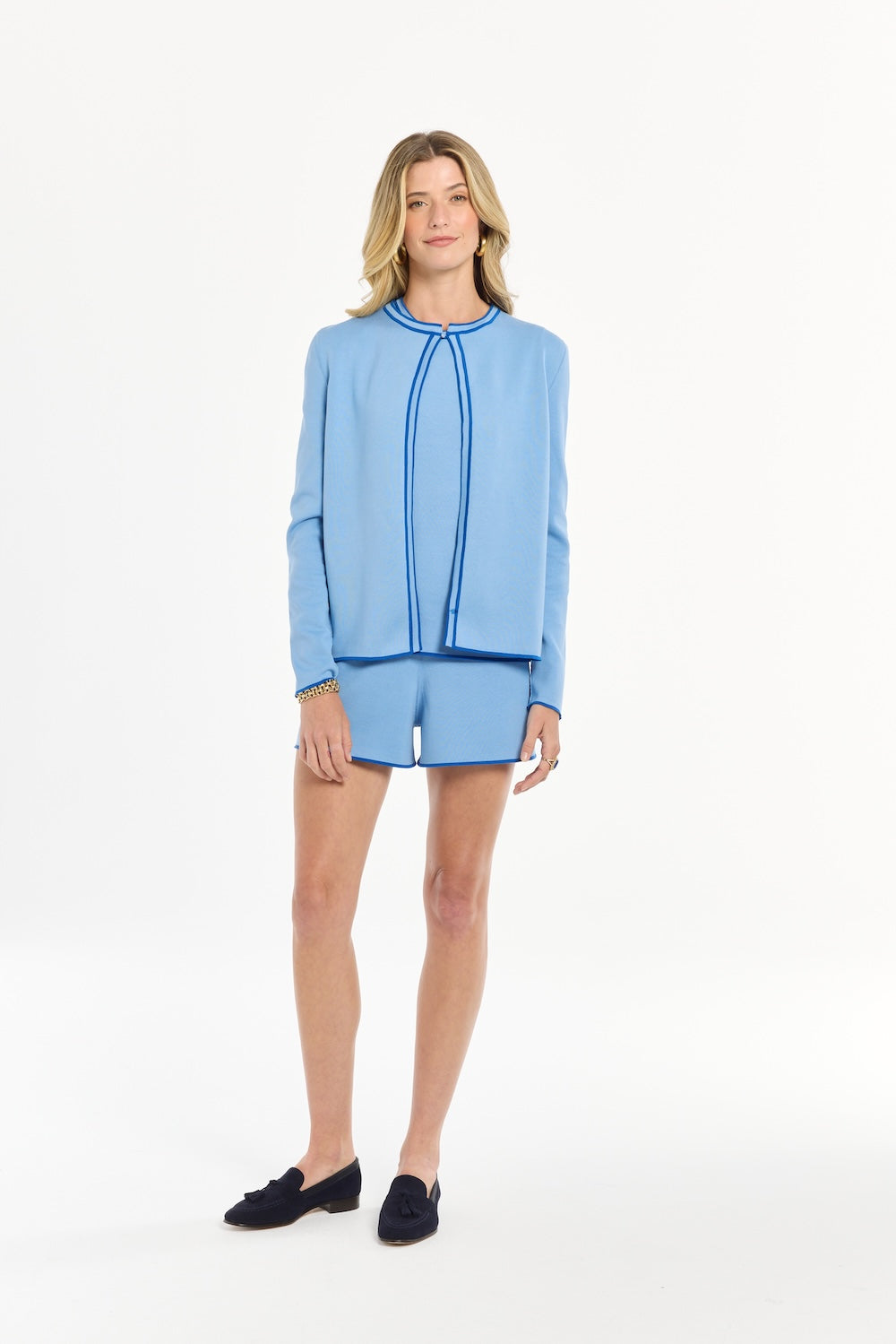 Woman wearing a blue cardigan in front of a white background