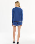 Woman wearing a blue outfit with white trim on a white background