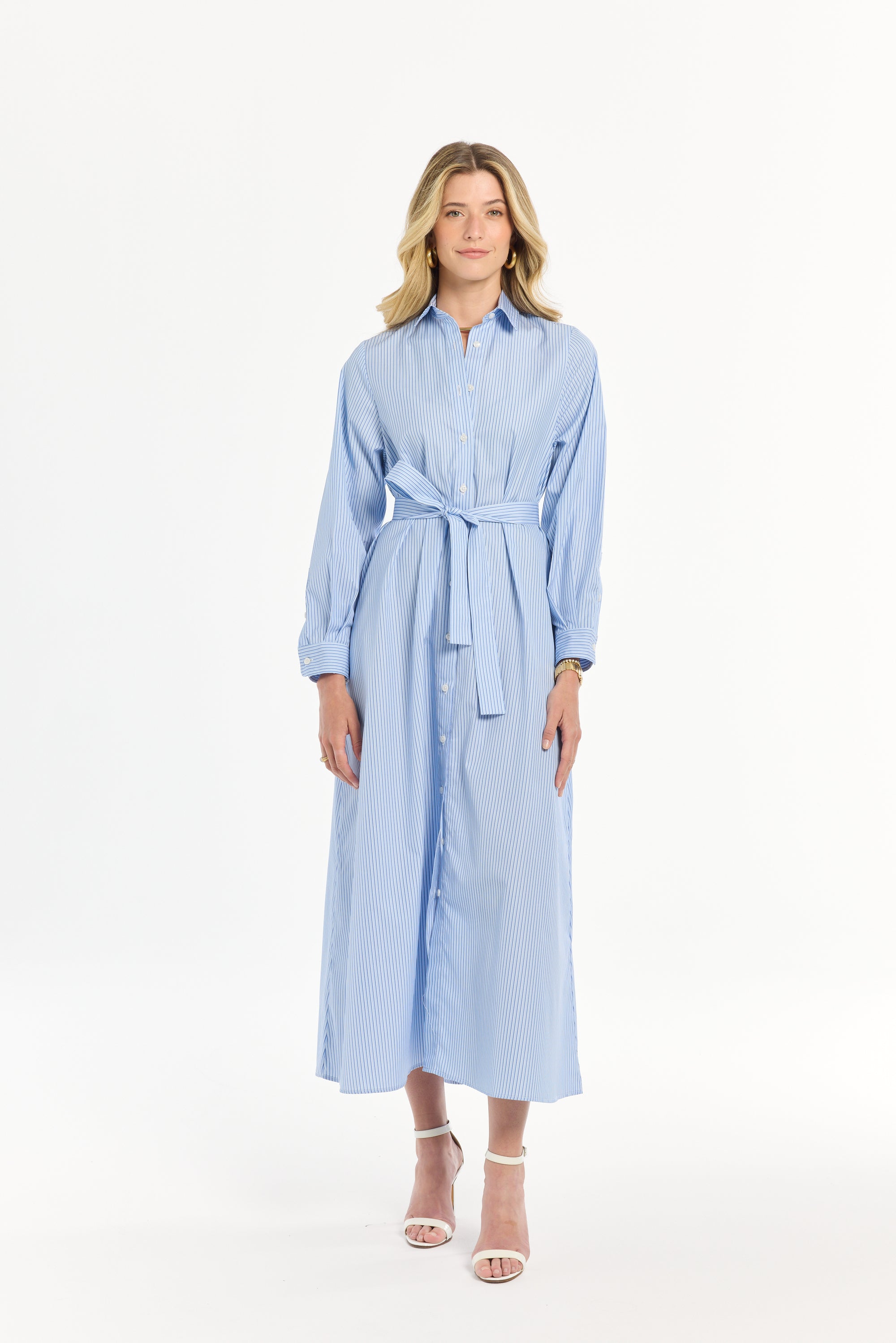 Woman wearing a light blue striped dress with a belt on a white background