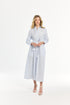 Woman wearing a long light blue and white striped dress on a white background