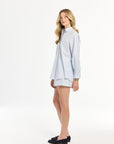 Woman wearing a light blue striped shirt and shorts on a white background