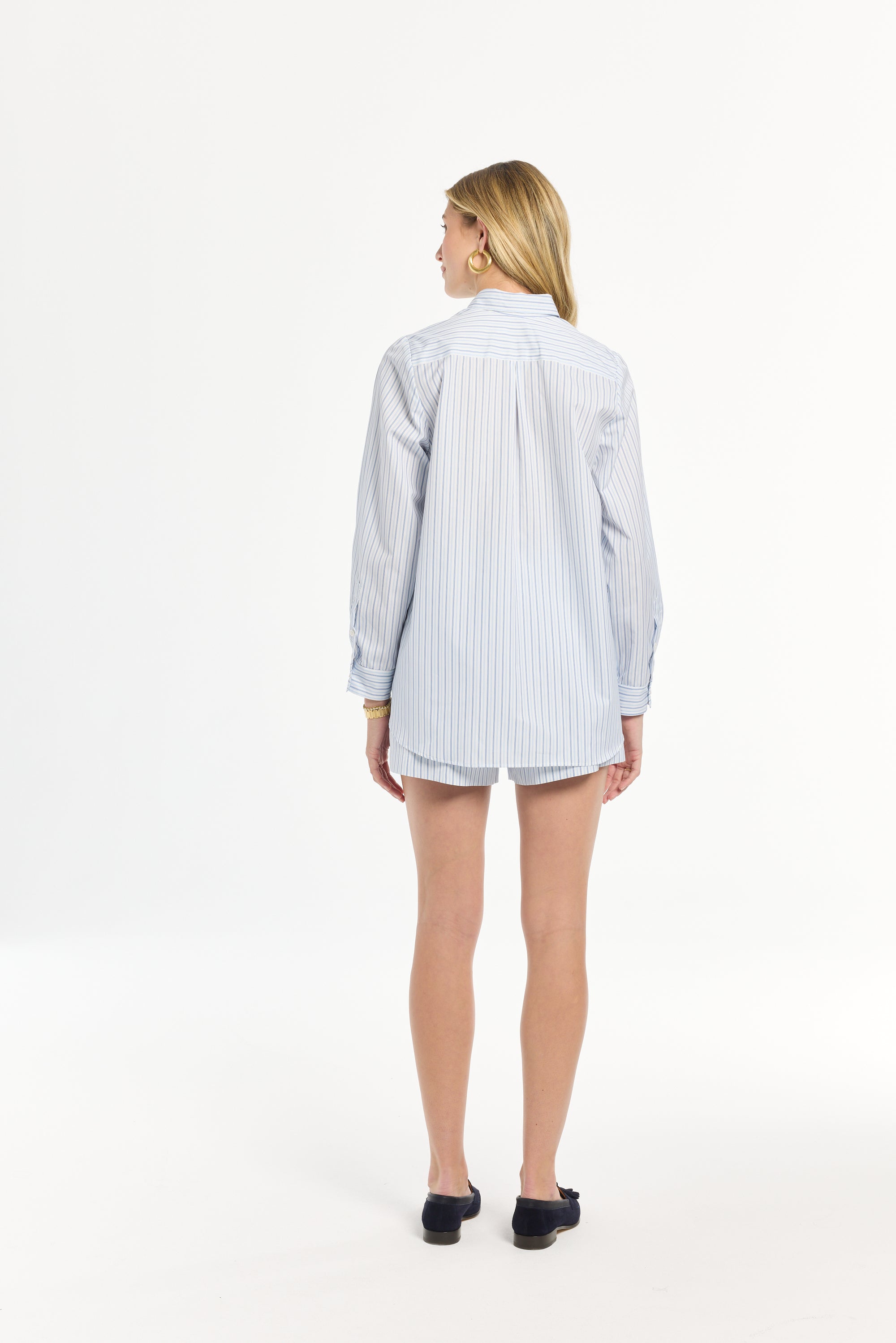 Woman wearing a light blue and white striped shirt on a white background