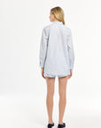 Woman wearing a light blue and white striped shirt on a white background