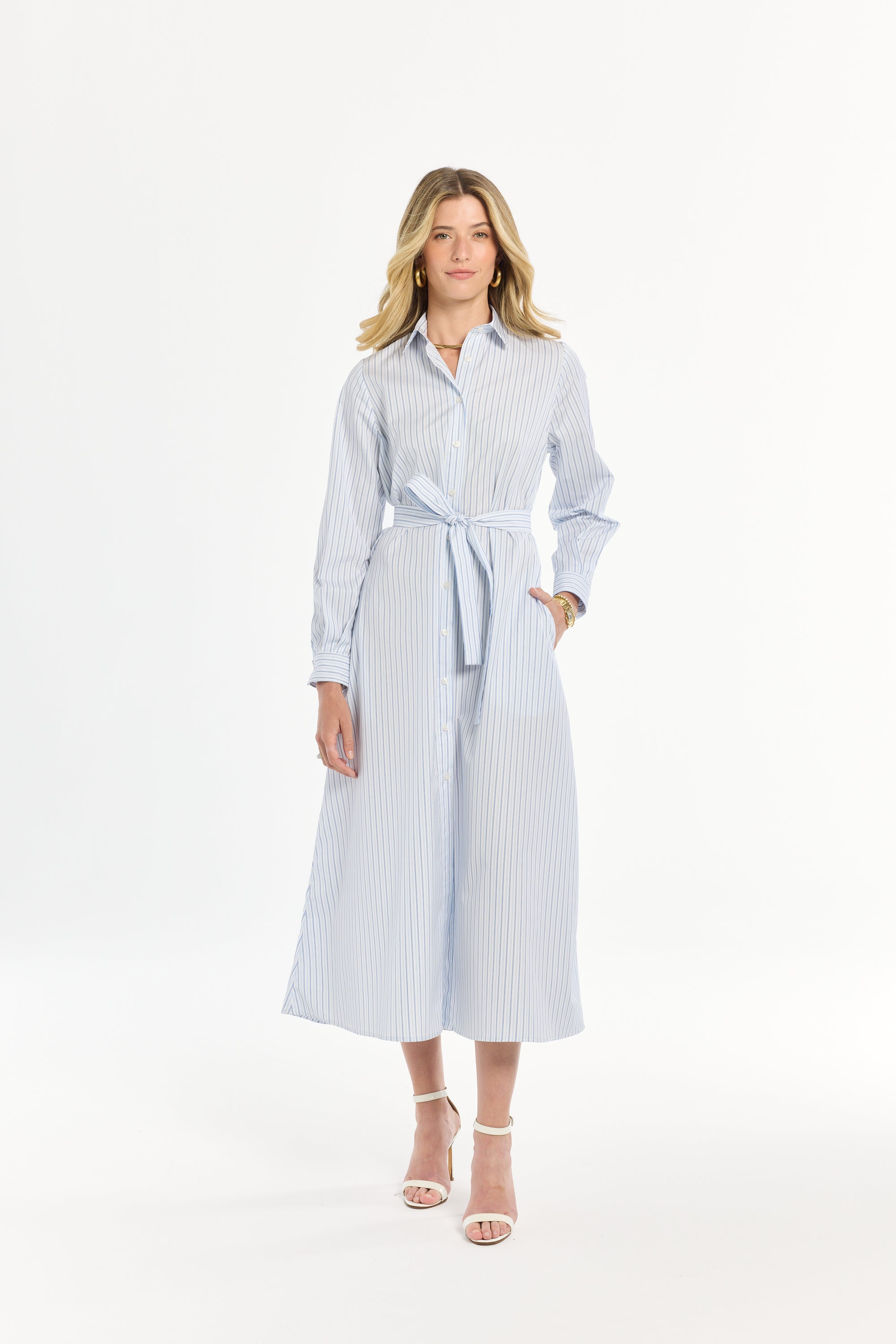 Woman wearing a blue and white striped dress with a belt on a white background