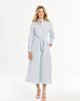 Woman wearing a blue and white striped dress with a belt on a white background