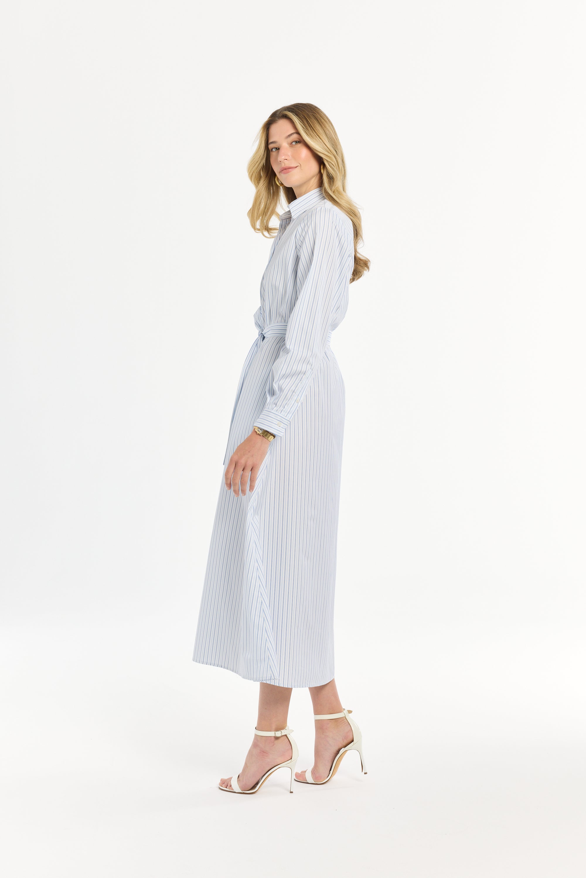 Woman wearing a light blue and white striped maxi length dress on a white background