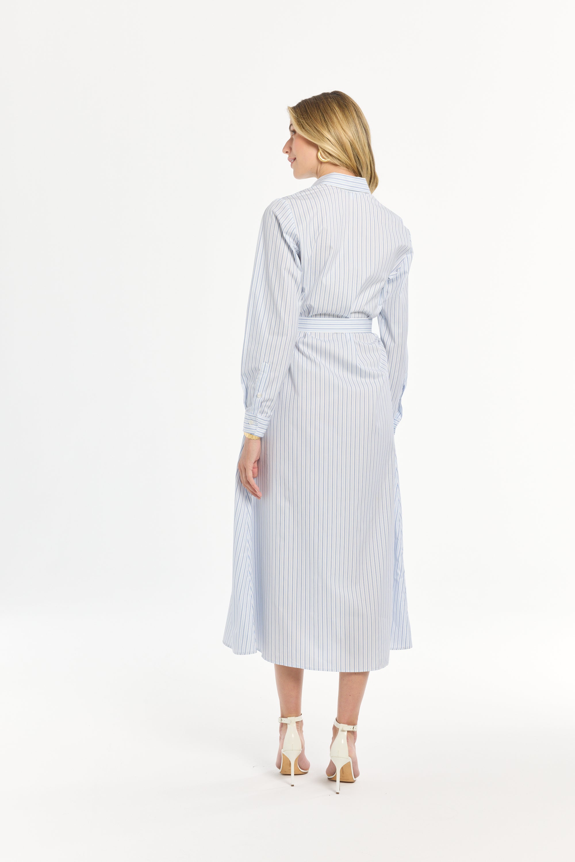 Woman wearing a light blue and white striped dress on a plain background