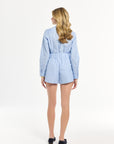 Woman wearing a light blue blouse and shorts on a white background