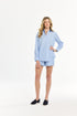 Woman wearing a light blue shirt and shorts on a white background