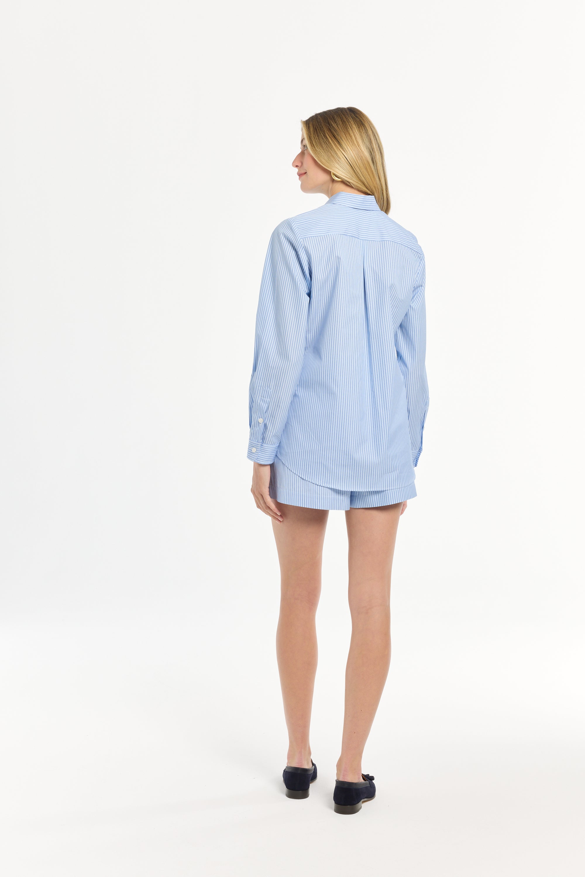 Woman wearing a light blue striped top and matching shorts on a white background
