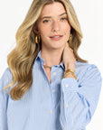 Woman wearing a blue striped shirt with jewelry on a white background
