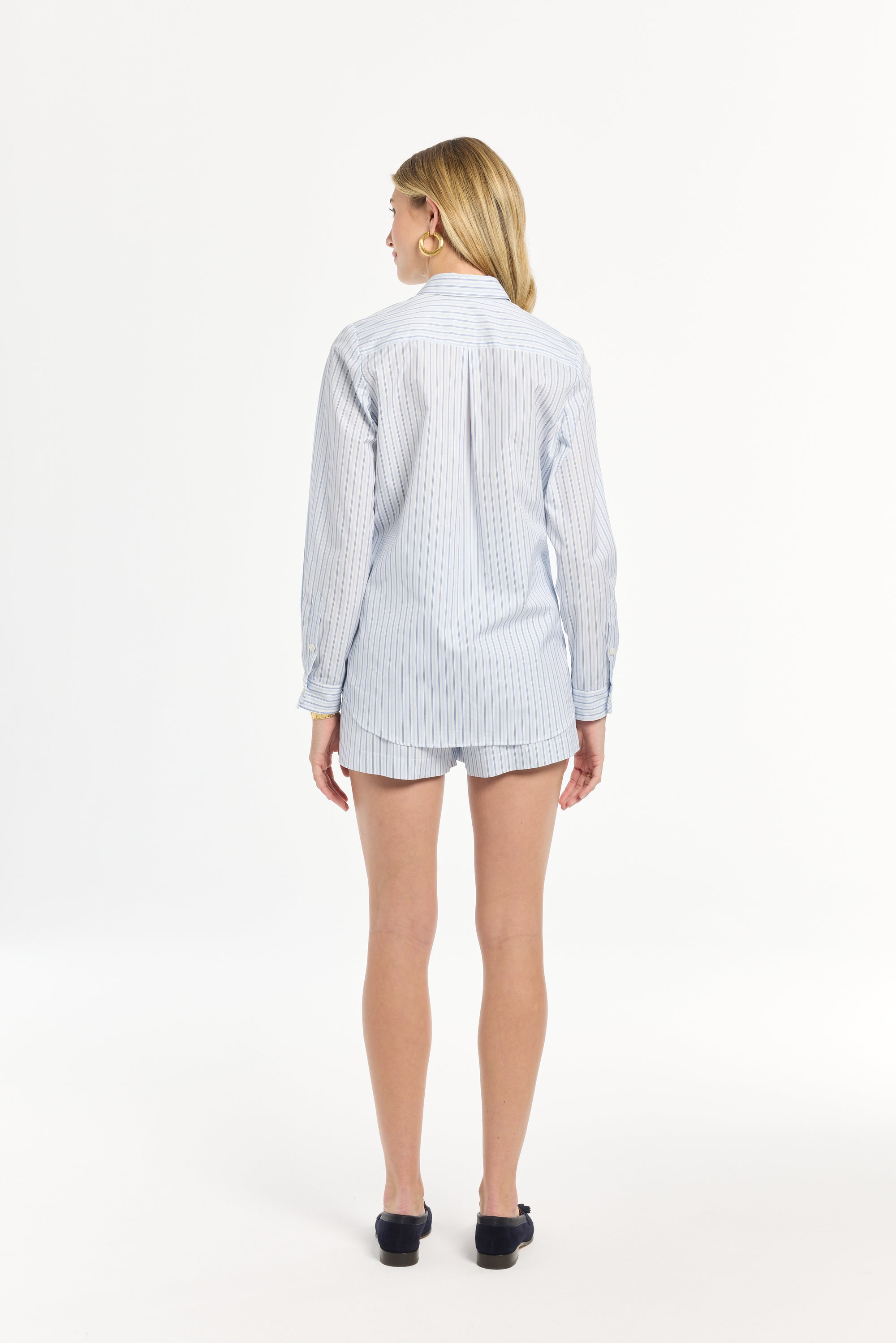 Person wearing a light blue striped shirt and shorts on a white background