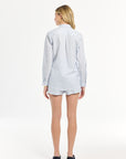 Person wearing a light blue striped shirt and shorts on a white background