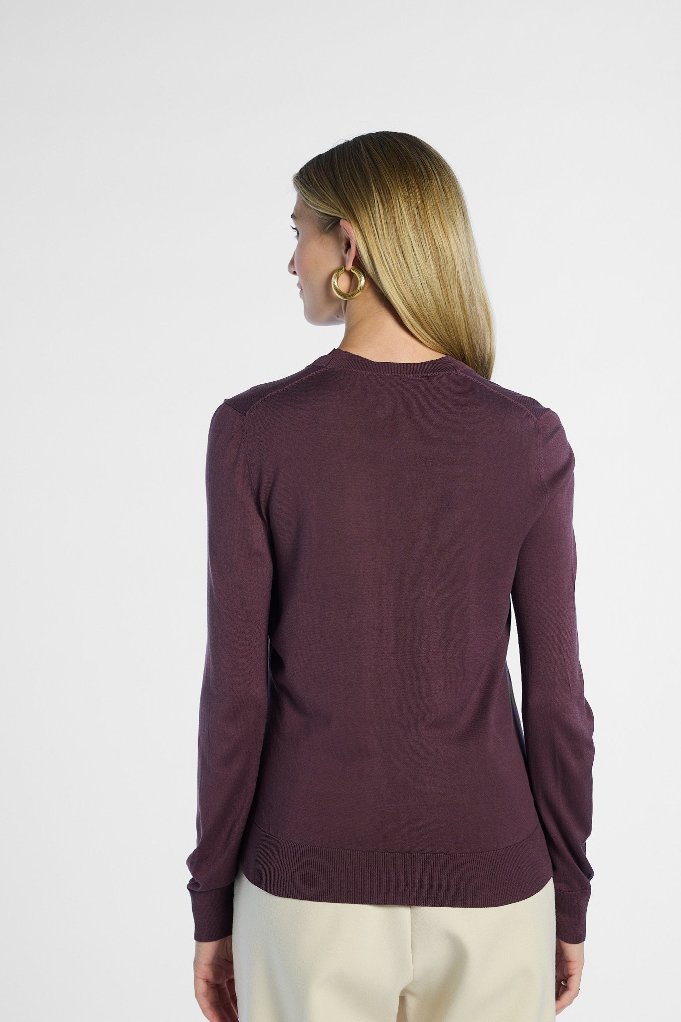 Back of a woman wearing a purple sweater on a white background