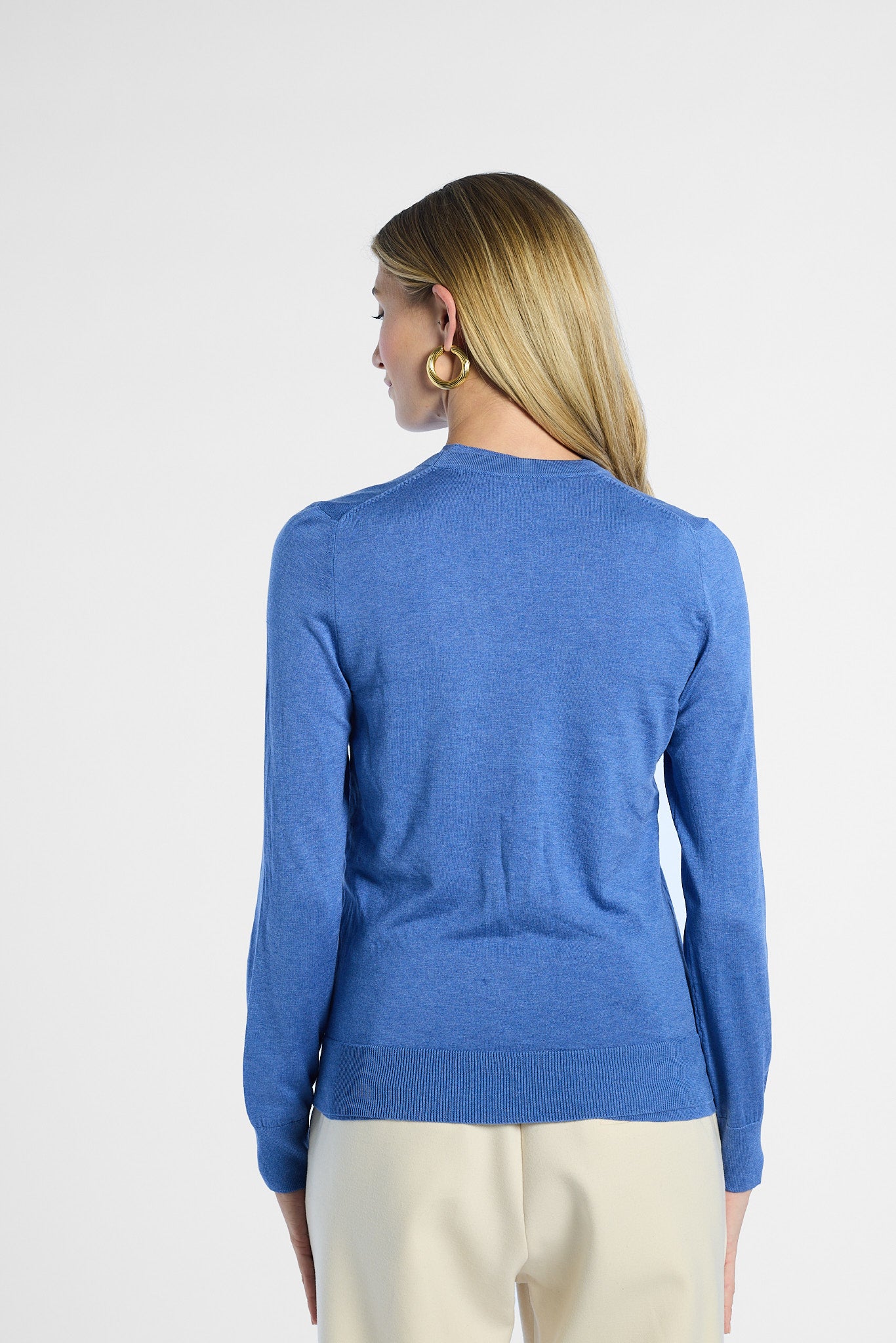 Back profile of a woman wearing a blue sweater on a white background